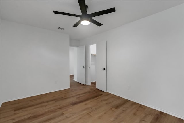 unfurnished room with a ceiling fan, light wood-style floors, and baseboards