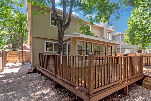 rear view of house with a wooden deck, fence, and a gate