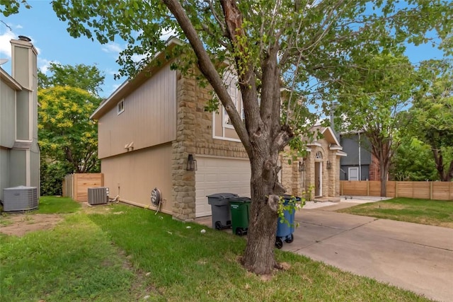 view of side of property featuring central air condition unit, an attached garage, concrete driveway, and stone siding