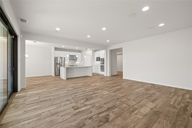 5213 Fresno Ave, Pflugerville, TX 78660 - unfurnished living room with light wood finished floors and recessed lighting