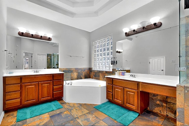 full bath featuring a shower stall, a garden tub, two vanities, and stone finish floors