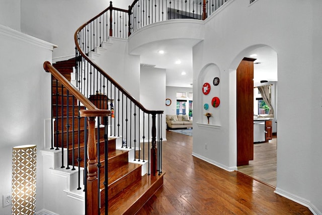 16525 Broadbay Dr, Austin, TX 78717 - stairway featuring arched walkways, healthy amount of natural light, wood finished floors, a high ceiling, and baseboards