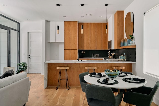 1140 Northwestern Ave Unit 2, Austin, TX 78702 - kitchen featuring brown cabinets, modern cabinets, a peninsula, light wood-style floors, and light countertops