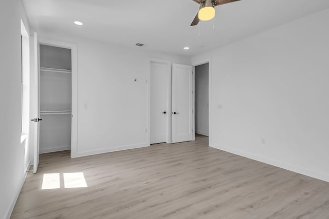 214 Ulupau Cir, Bastrop, TX 78602 - unfurnished bedroom featuring light wood-style floors, recessed lighting, ceiling fan, and multiple closets