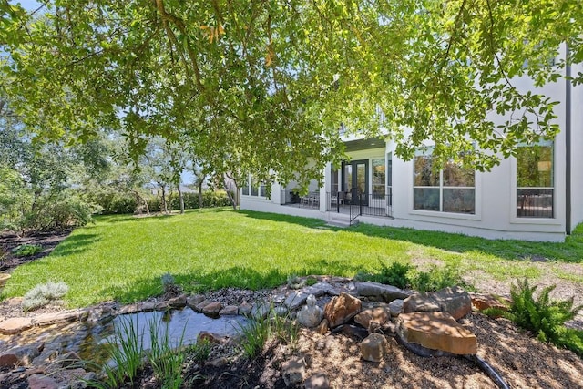 view of grassy yard featuring a small pond