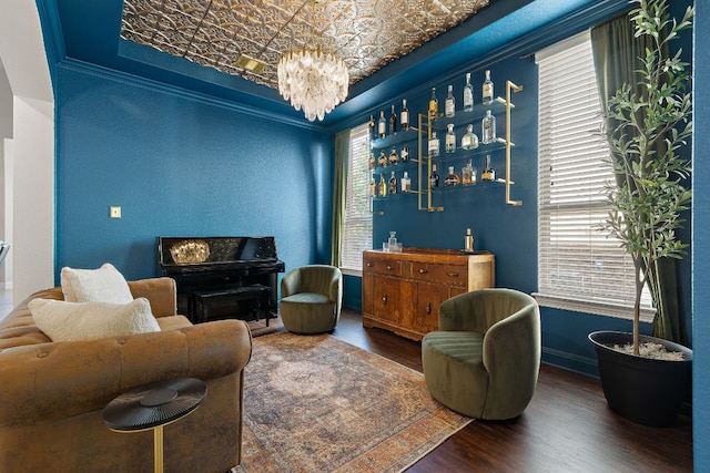 living area featuring wood finished floors, a chandelier, crown molding, and baseboards