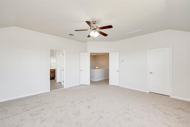unfurnished bedroom with vaulted ceiling, light colored carpet, baseboards, ensuite bath, and ceiling fan