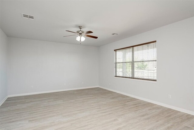spare room featuring ceiling fan, light wood finished floors, and baseboards