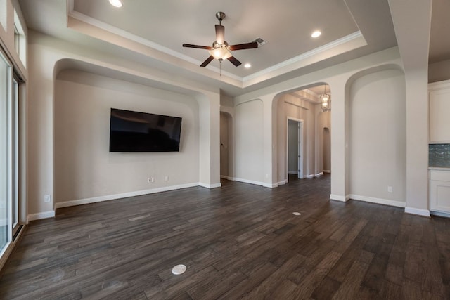 unfurnished living room featuring a raised ceiling, arched walkways, ceiling fan, dark wood finished floors, and recessed lighting