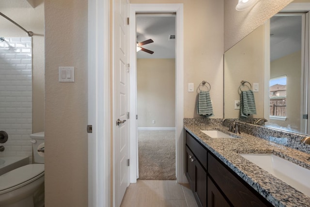 full bathroom featuring toilet, ceiling fan, double vanity, bathing tub / shower combination, and a textured wall