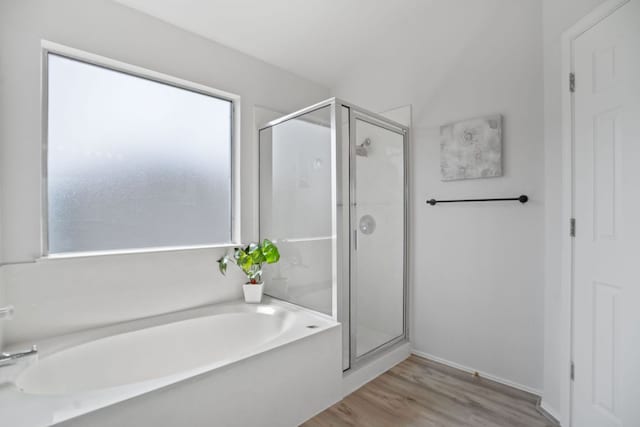 full bath featuring a stall shower, a bath, and wood finished floors