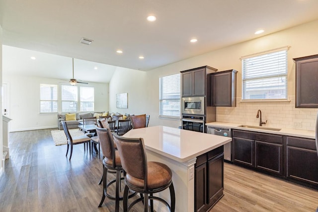 3805 Eland Dr, Pflugerville, TX 78660 - kitchen with a sink, appliances with stainless steel finishes, a kitchen island, a breakfast bar, and light countertops