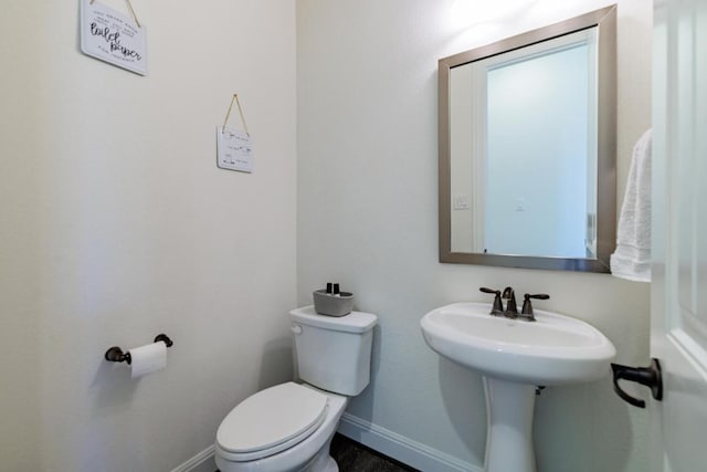 half bathroom featuring toilet and baseboards