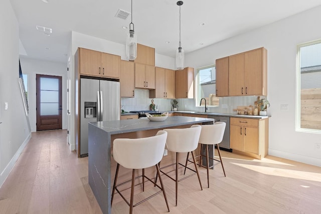 6406 Cannonleague Dr Unit 1, Austin, TX 78745 - kitchen with stainless steel appliances, light wood finished floors, decorative backsplash, baseboards, and a breakfast bar