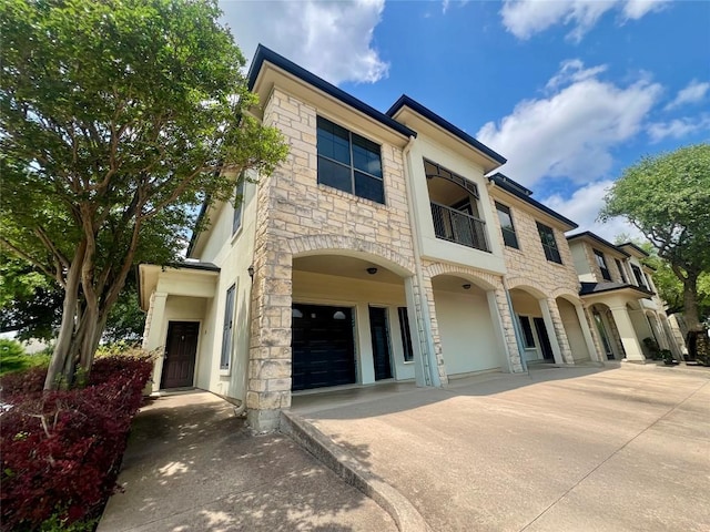 7701 Rialto Blvd Unit 1328, Austin, TX 78735 - view of front facade featuring stone siding, a balcony, and concrete driveway