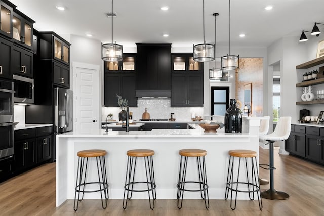 1026 Painted Horse Dr, Georgetown, TX 78633 - kitchen featuring stainless steel appliances, dark cabinetry, backsplash, a large island with sink, and recessed lighting