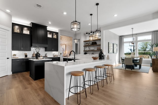 1026 Painted Horse Dr, Georgetown, TX 78633 - kitchen featuring dark cabinetry, a center island, recessed lighting, backsplash, and a kitchen breakfast bar