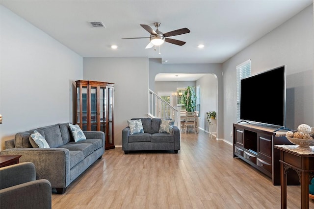 446 Thunder Valley Trl, Georgetown, TX 78626 - living area featuring arched walkways, light wood-type flooring, stairs, a ceiling fan, and a chandelier