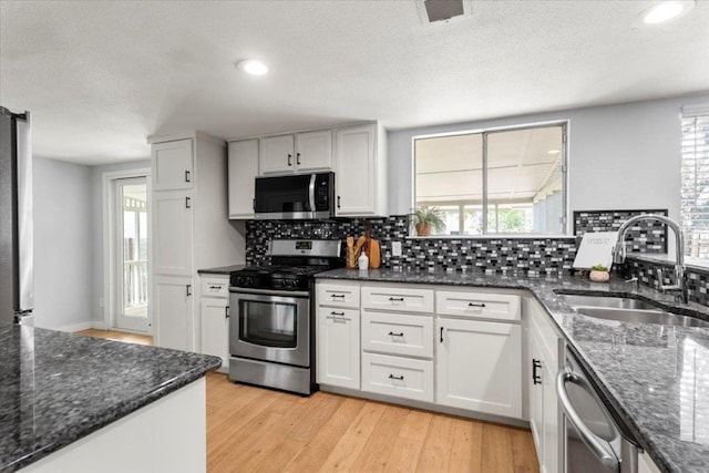 kitchen with stainless steel appliances, a sink, tasteful backsplash, white cabinets, and recessed lighting