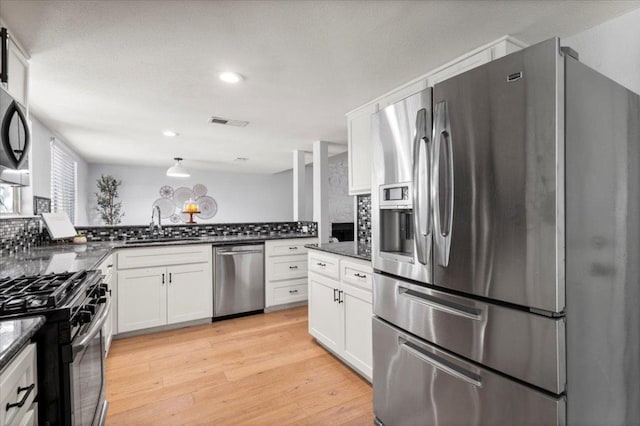 kitchen featuring appliances with stainless steel finishes, tasteful backsplash, white cabinetry, light wood-type flooring, and recessed lighting