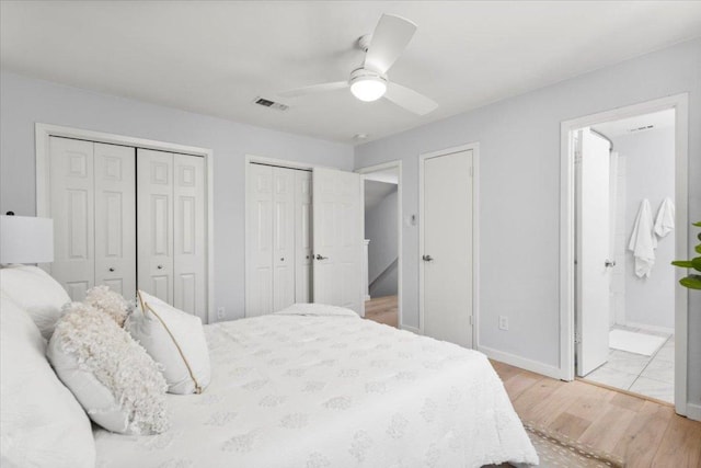 bedroom with two closets, light wood-style floors, ensuite bath, baseboards, and a ceiling fan