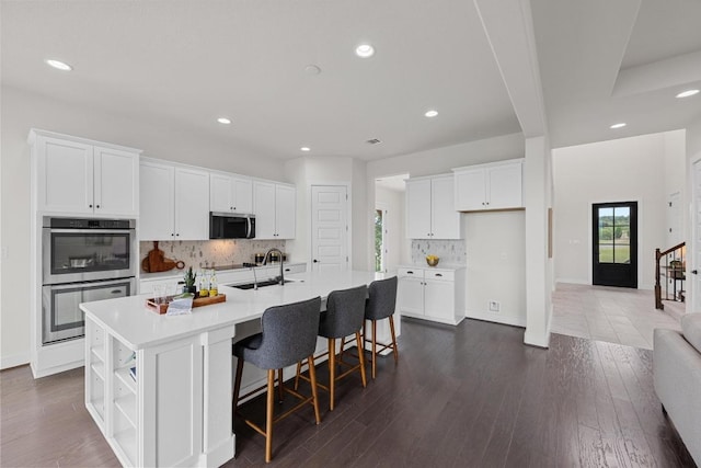 kitchen featuring stainless steel appliances, white cabinetry, a sink, recessed lighting, and decorative backsplash