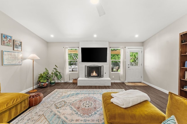 living room with baseboards, a brick fireplace, wood finished floors, and recessed lighting