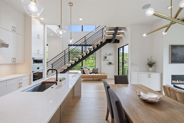 903 Alexia Ln, Austin, TX 78746 - kitchen featuring a sink, open floor plan, light wood-style flooring, decorative light fixtures, and white cabinets