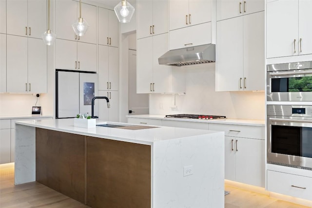 903 Alexia Ln, Austin, TX 78746 - kitchen with freestanding refrigerator, under cabinet range hood, gas cooktop, light wood-style flooring, and light countertops
