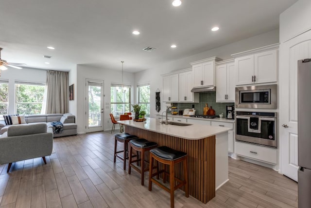 1314 Overture Pl, Round Rock, TX 78681 - kitchen with appliances with stainless steel finishes, a sink, open floor plan, a breakfast bar, and a ceiling fan