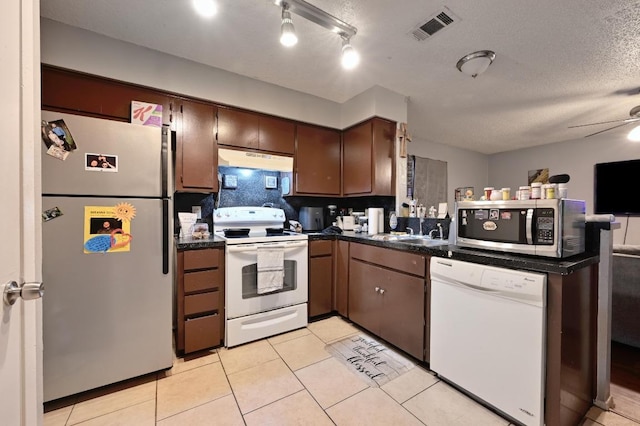 5405 Rose Hill Cir, Austin, TX 78745 - kitchen with white appliances, dark countertops, under cabinet range hood, a peninsula, and a textured ceiling