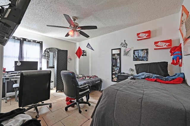 bedroom featuring light tile patterned floors, a textured ceiling, a desk, and ceiling fan