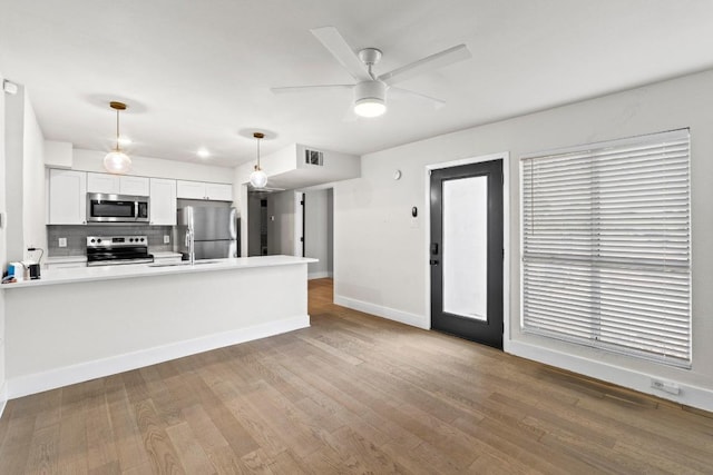 909 Reinli St Unit 101, Austin, TX 78751 - kitchen featuring appliances with stainless steel finishes, decorative light fixtures, a peninsula, tasteful backsplash, and a ceiling fan