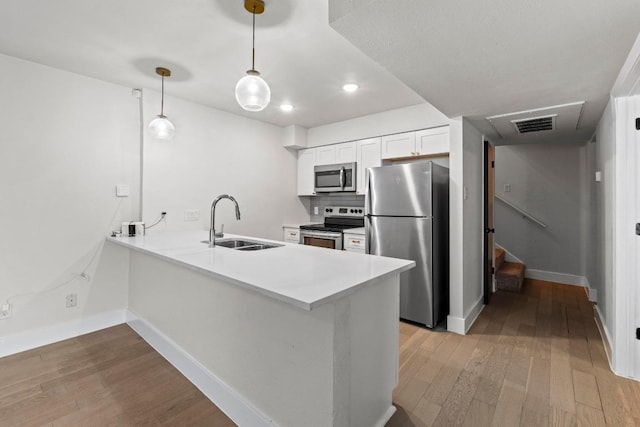 909 Reinli St Unit 101, Austin, TX 78751 - kitchen with stainless steel appliances, wood-type flooring, a peninsula, white cabinetry, and light countertops