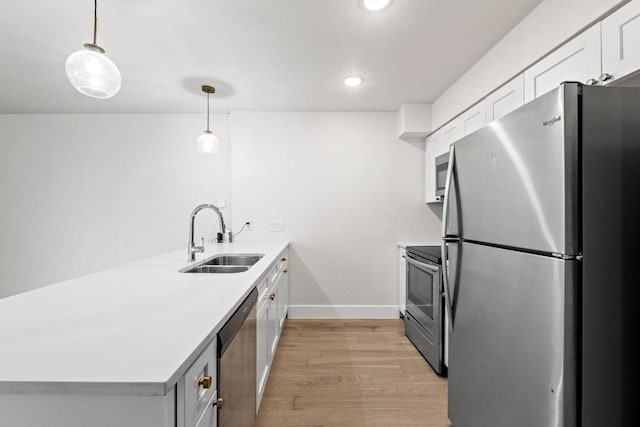 909 Reinli St Unit 101, Austin, TX 78751 - kitchen featuring appliances with stainless steel finishes, a sink, a peninsula, light wood-style floors, and light countertops