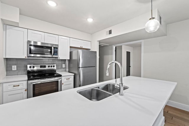 909 Reinli St Unit 101, Austin, TX 78751 - kitchen featuring stainless steel appliances, a sink, light countertops, white cabinetry, and recessed lighting