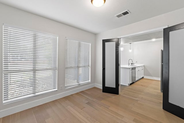 909 Reinli St Unit 101, Austin, TX 78751 - kitchen with stainless steel dishwasher, a sink, baseboards, and light countertops