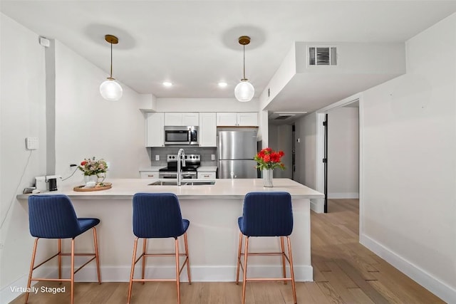 909 Reinli St Unit 101, Austin, TX 78751 - kitchen featuring stainless steel appliances, a sink, a breakfast bar, a peninsula, and recessed lighting