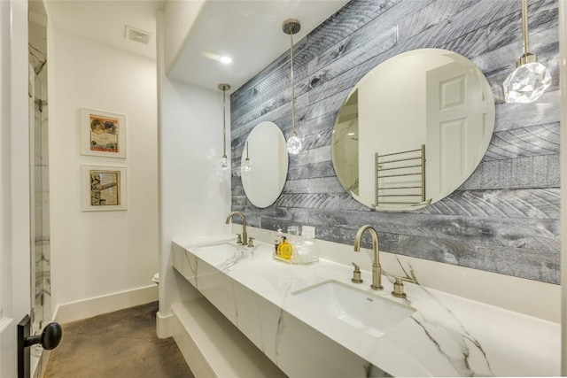 bathroom featuring toilet, baseboards, double vanity, and concrete flooring