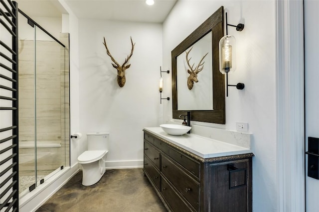 bathroom with a shower stall, toilet, vanity, and baseboards