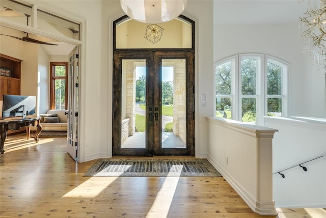 foyer featuring french doors, plenty of natural light, wood finished floors, and baseboards