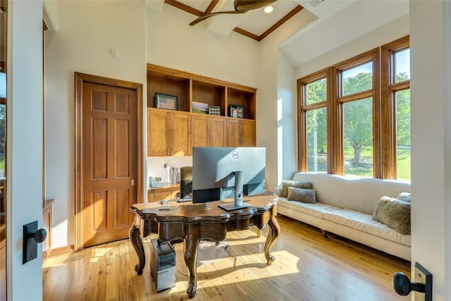 office space featuring crown molding, light wood-style floors, and a high ceiling