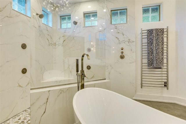 bathroom with healthy amount of natural light, a freestanding bath, and a marble finish shower