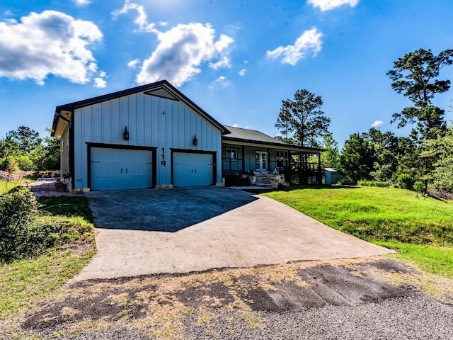 119 E Wiamea Ct, Bastrop, TX 78602 - view of front of house featuring board and batten siding, a porch, driveway, an attached garage, and a front lawn