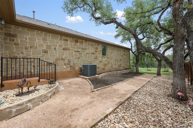 100 Royal Oak Dr, Georgetown, TX 78628 - view of property exterior with central air condition unit, fence, and stone siding