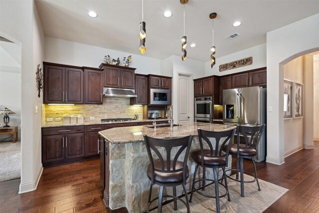 100 Royal Oak Dr, Georgetown, TX 78628 - kitchen with a sink, under cabinet range hood, stainless steel appliances, arched walkways, and an island with sink