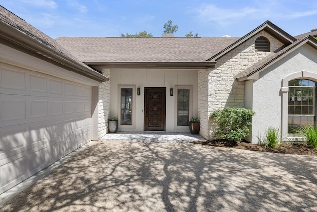 doorway to property featuring stone siding, concrete driveway, an attached garage, roof with shingles, and stucco siding