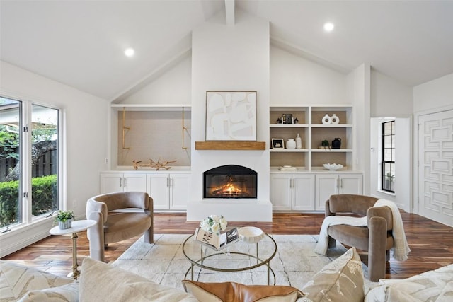 210 Hazeltine Dr, Lakeway, TX 78734 - living area with healthy amount of natural light, high vaulted ceiling, wood finished floors, a glass covered fireplace, and beamed ceiling