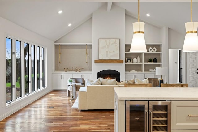 210 Hazeltine Dr, Lakeway, TX 78734 - living room featuring beverage cooler, a warm lit fireplace, light wood-style floors, high vaulted ceiling, and recessed lighting