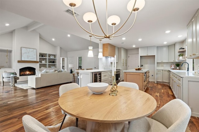 210 Hazeltine Dr, Lakeway, TX 78734 - dining room with wine cooler, dark wood-style floors, a warm lit fireplace, recessed lighting, and a chandelier
